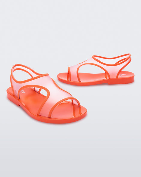 An angled front and side view of a pair of transparent orange Melissa Bikini Sandal with two transparent orange straps conjoining in the middle and an orange insole.