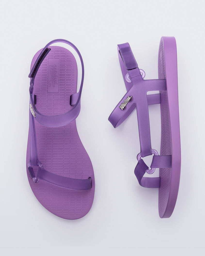Top and side view of a pair of Melissa Sun Downtown sandals with transparent lilac front cross and back ankle straps and a lilac purple sole.