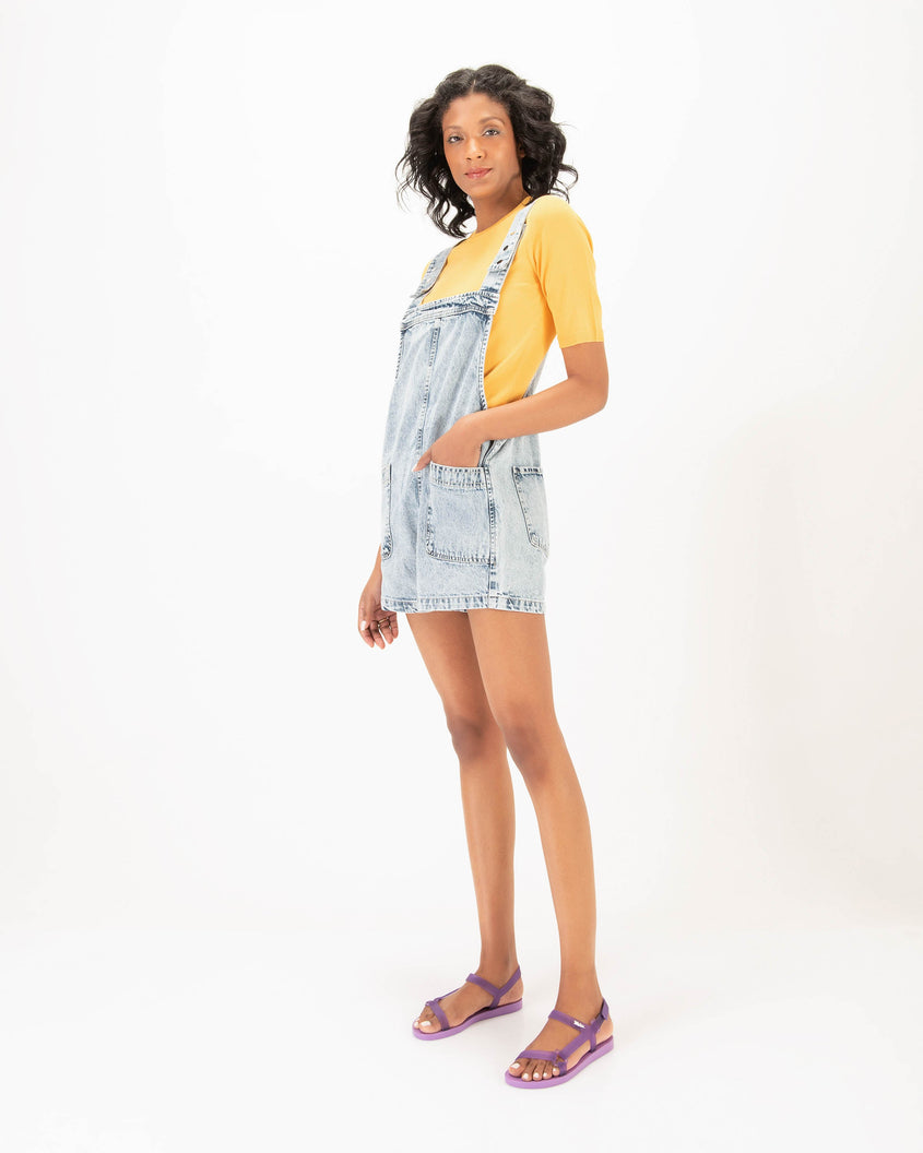 A model posing wearing a pair of Melissa Sun Downtown sandals with transparent lilac front cross and back ankle straps and a lilac purple sole.