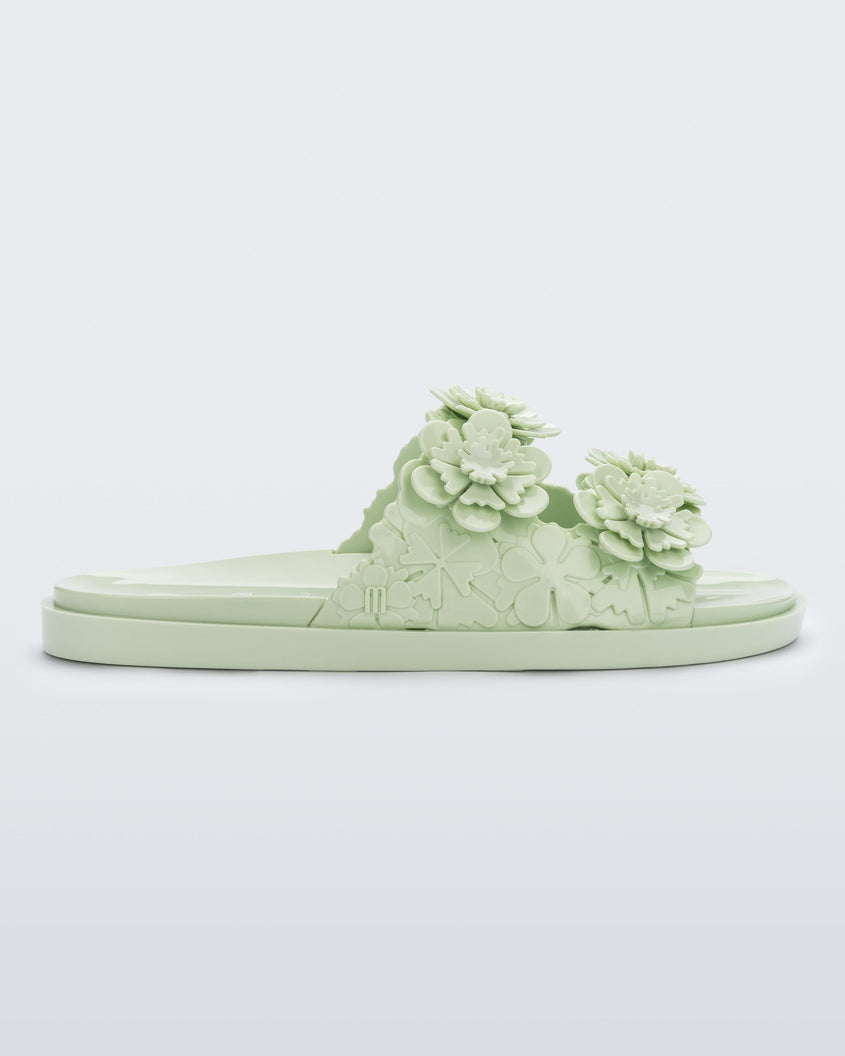 Side view of a Melissa Wide Blossom Slide in green with double floral embossed buckle straps and 3D flower appliques