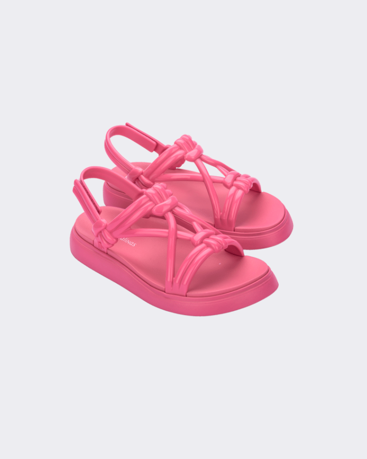 Angled view of a pair of Melissa Papete Essential pink sandals with straps.