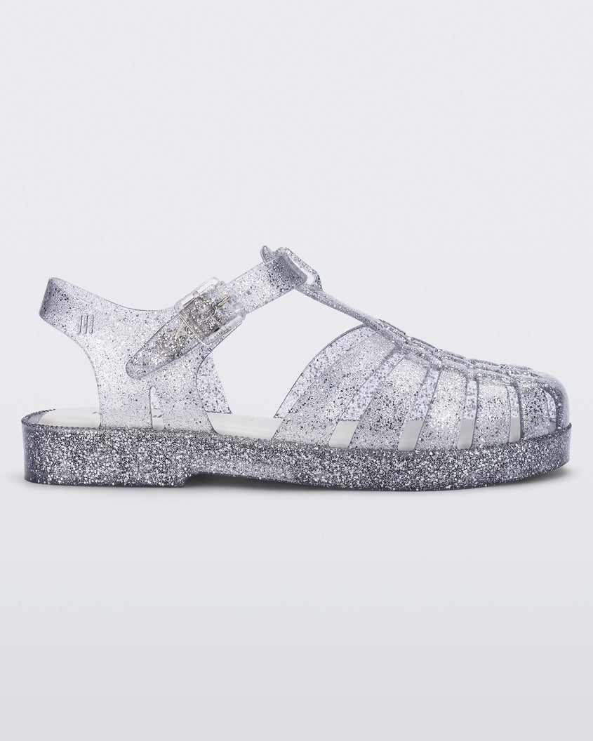 Side view of a Glass/Glitter/Sliver Mini Melissa Possession Shiny sandal with several straps and a clear silver glitter base.