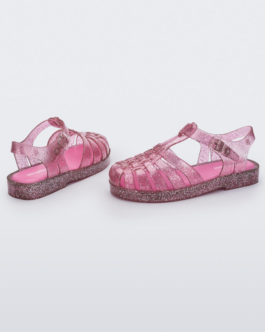 A side and back view of a pair Pink/Glitter/Silver Mini Melissa Possession Shiny sandals with several straps and a pink glitter base.