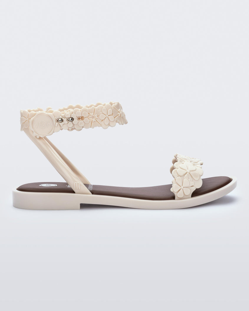 Side view of a beige/brown Melissa Wave Blossom Sandal with a floral detail front and ankle strap.