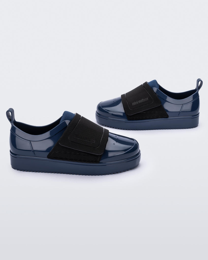 Side view of a pair of blue/black Mini Melissa Jelly Pop Sneakers with a blue base and a black velcro strap.