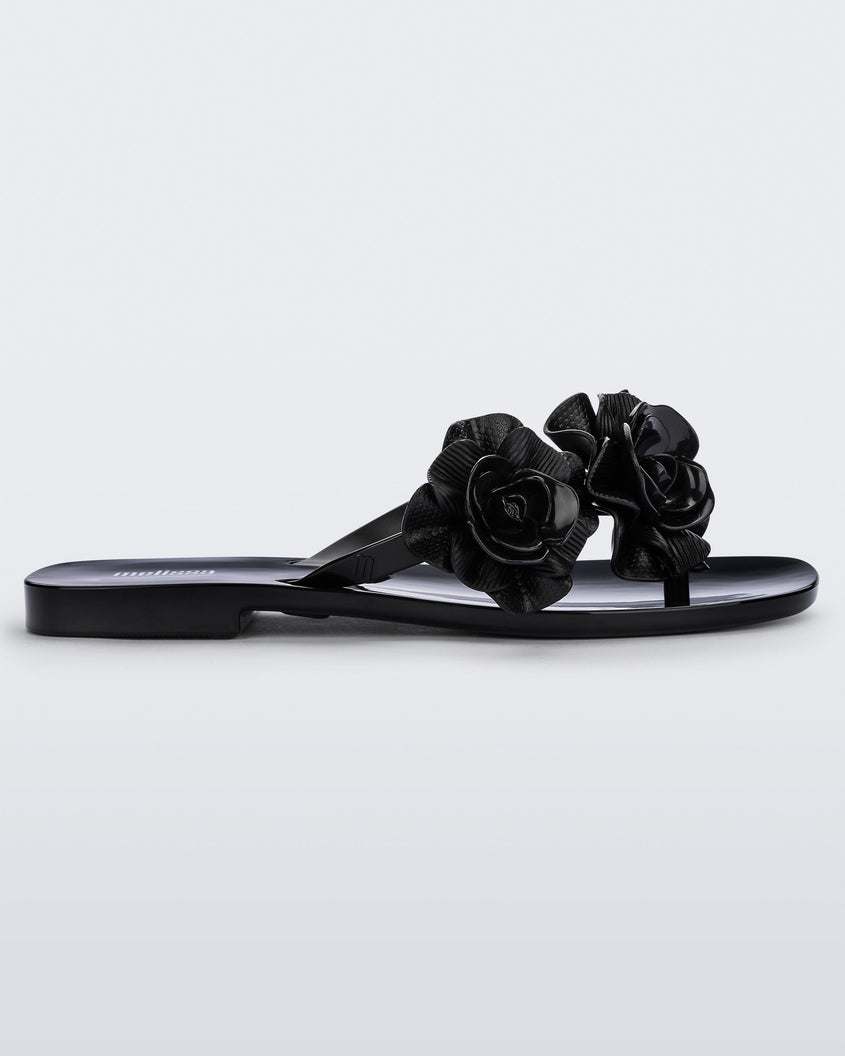 Side view of a black Melissa Harmomic Squared Garden flip flop with flowers on the straps.