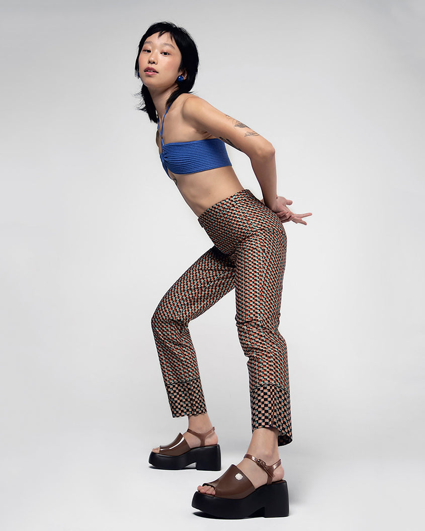 A model posing for a picture in a blue top, patterned brown bottoms and a pair of black/brown Melissa Pose platform sandals with a brown front strap, a clear brown ankle strap and a black sole.