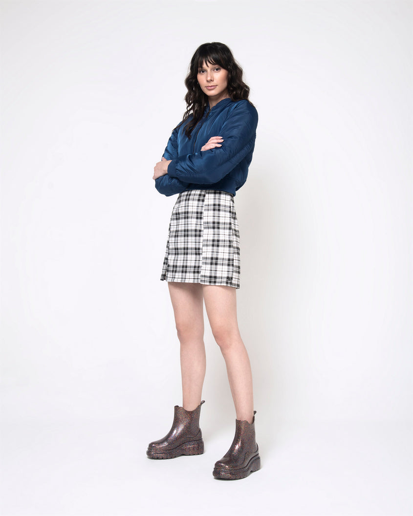 A model posing for a picture wearing a pair of clear glitter Melissa Grip multicolor glitter short rain boots.