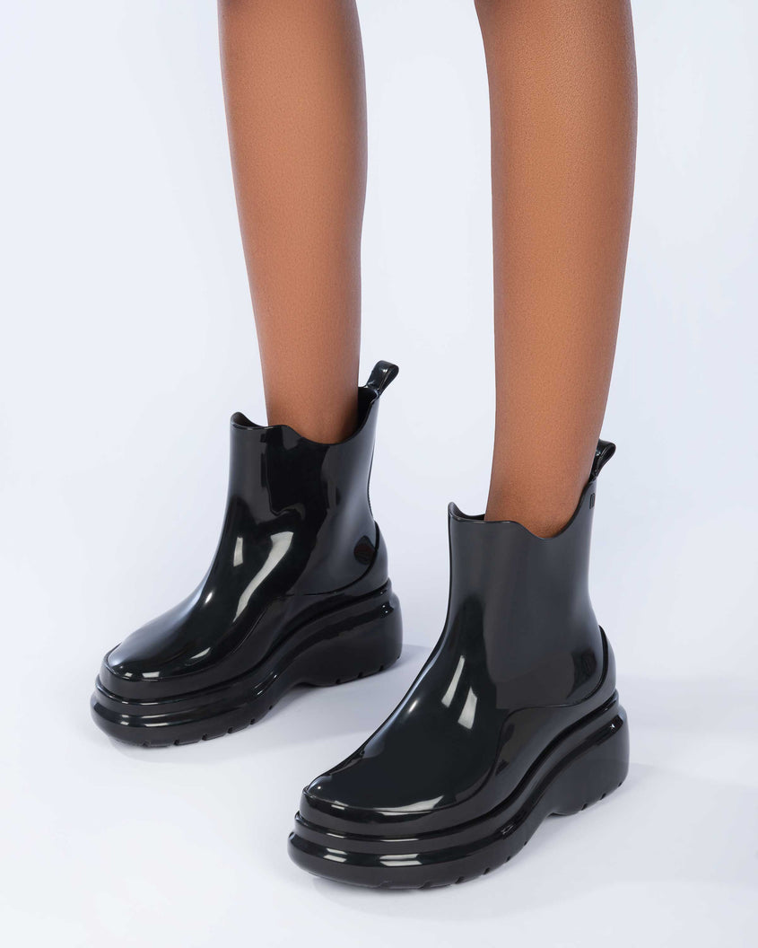 A model's legs wearing a pair of black Melissa Grip black short rain boots.