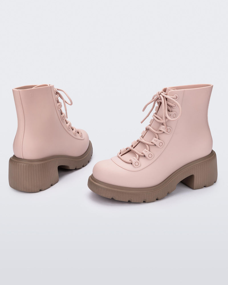 An angled back and side view of a pair of brown/pink Melissa Cosmo boots with a pink base, laces and a brown heel sole, laying on their side.
