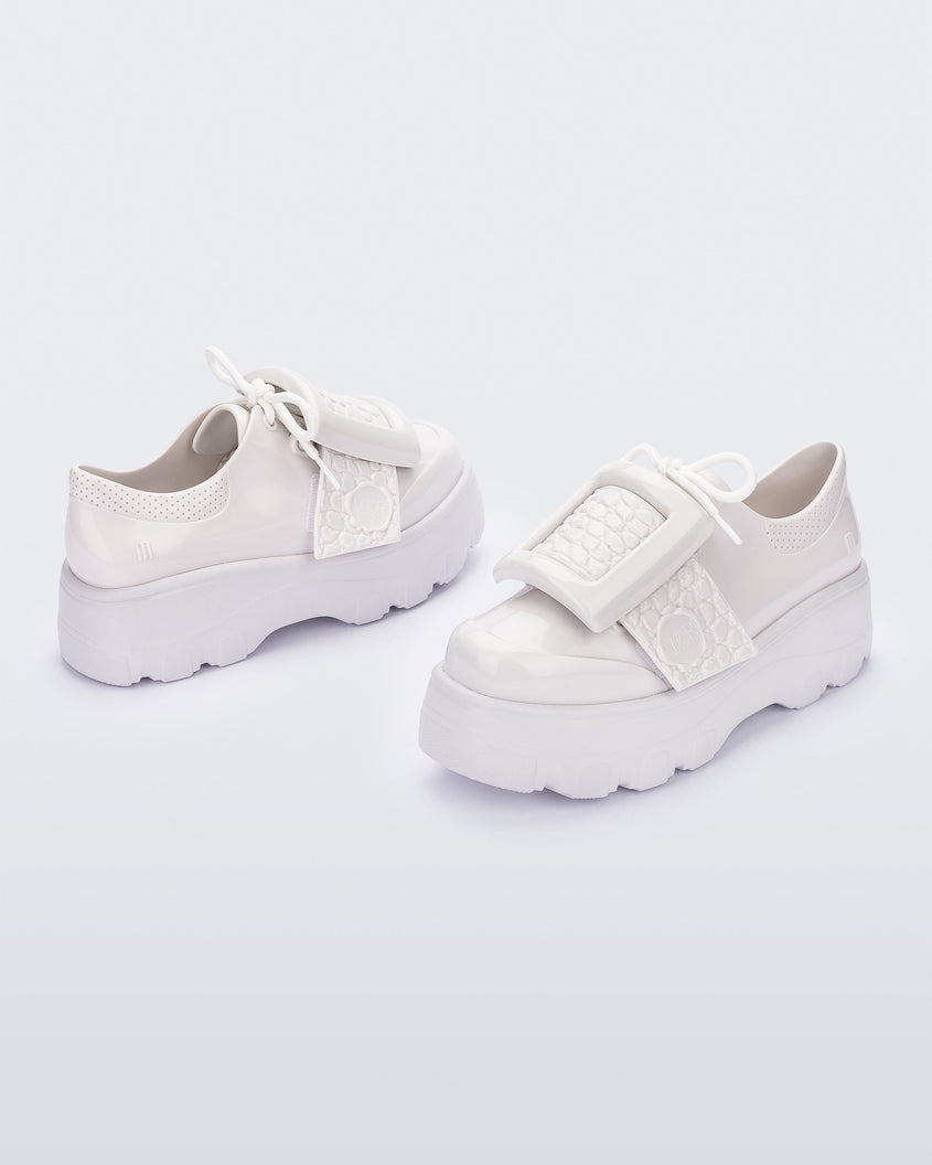 Angled view of a pair of white Melissa Buckle Up Kick Off platform sneakers.