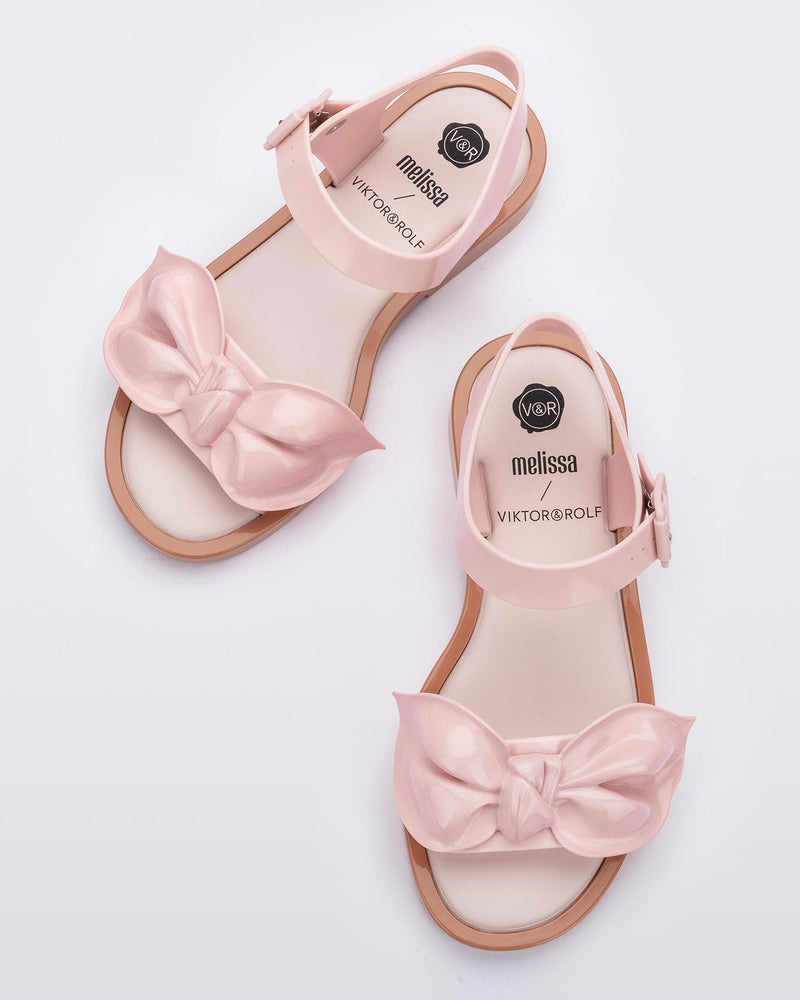 Top view of a pair of Melissa Tie Mar sandals with beige sole, pink ankle straps with buckle closure and pink 3D bow detail on front straps