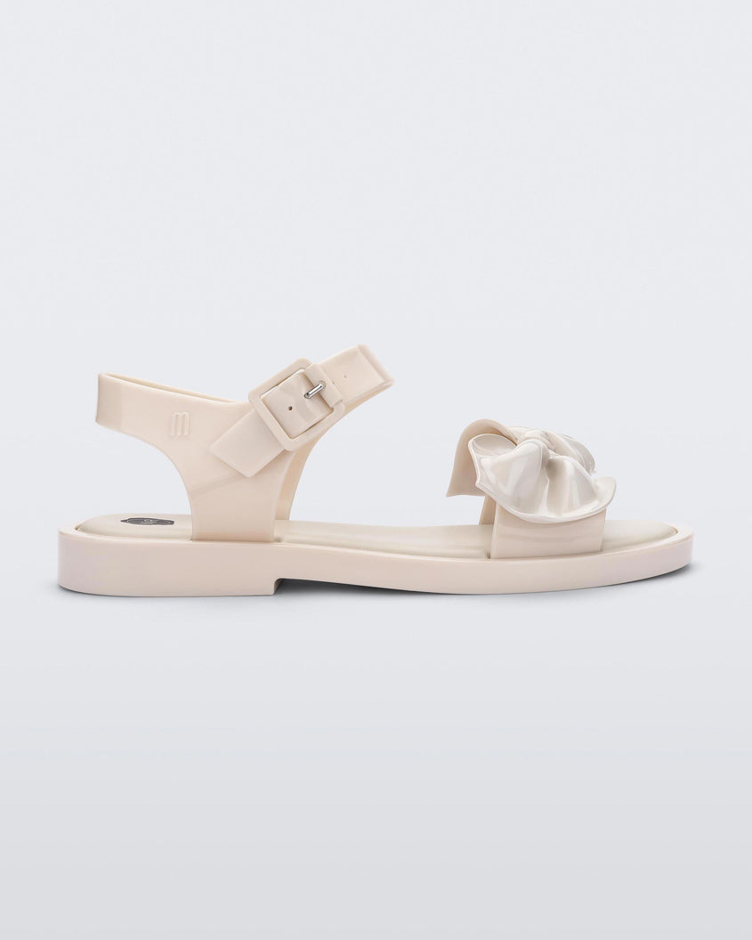 Side view of a Beige/Beige Melissa Tie Mar Sandal with a beige base, an ankle strap and a front strap with a beige bow on the front.