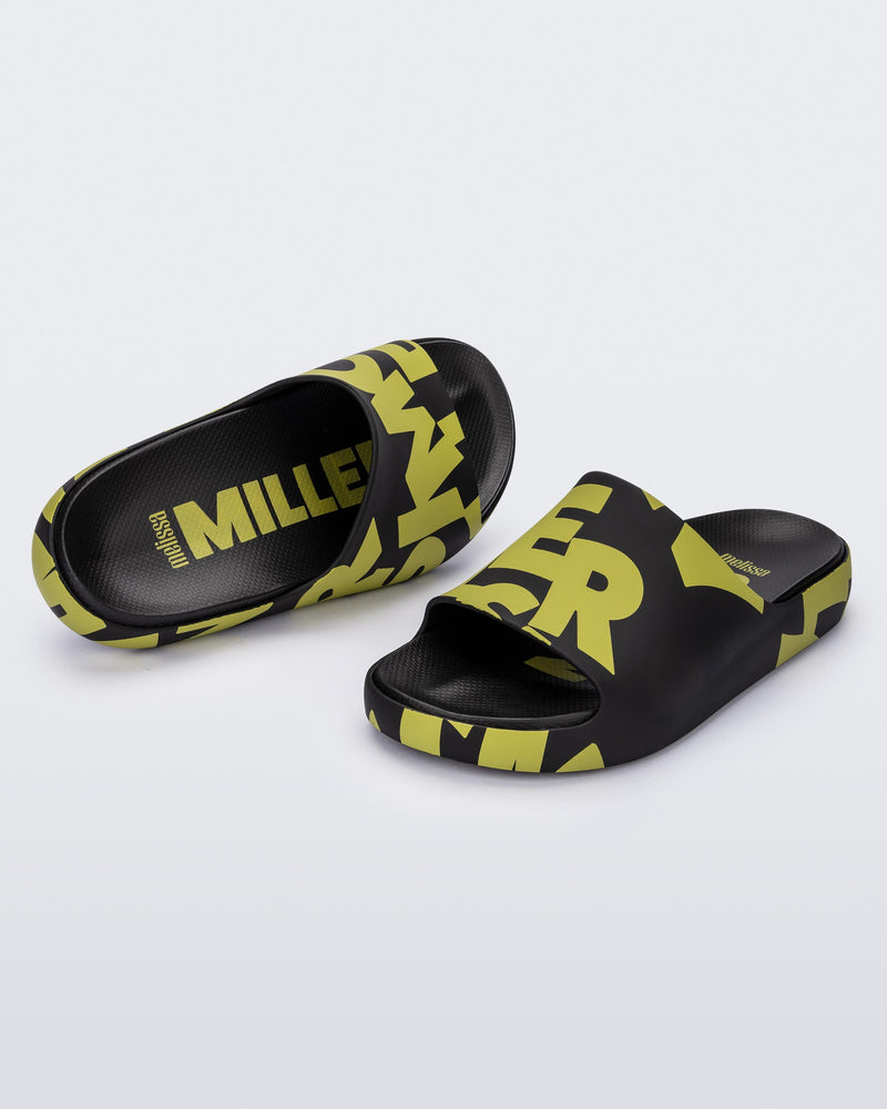An angled top and front view of a pair of Black & Kiwi Logo Scramble Melissa Cloud slides with a green simon miller letter scrambled text on the base and a black insole reading in green "Melissa Miller" and "Melissa Simon" on different shoes