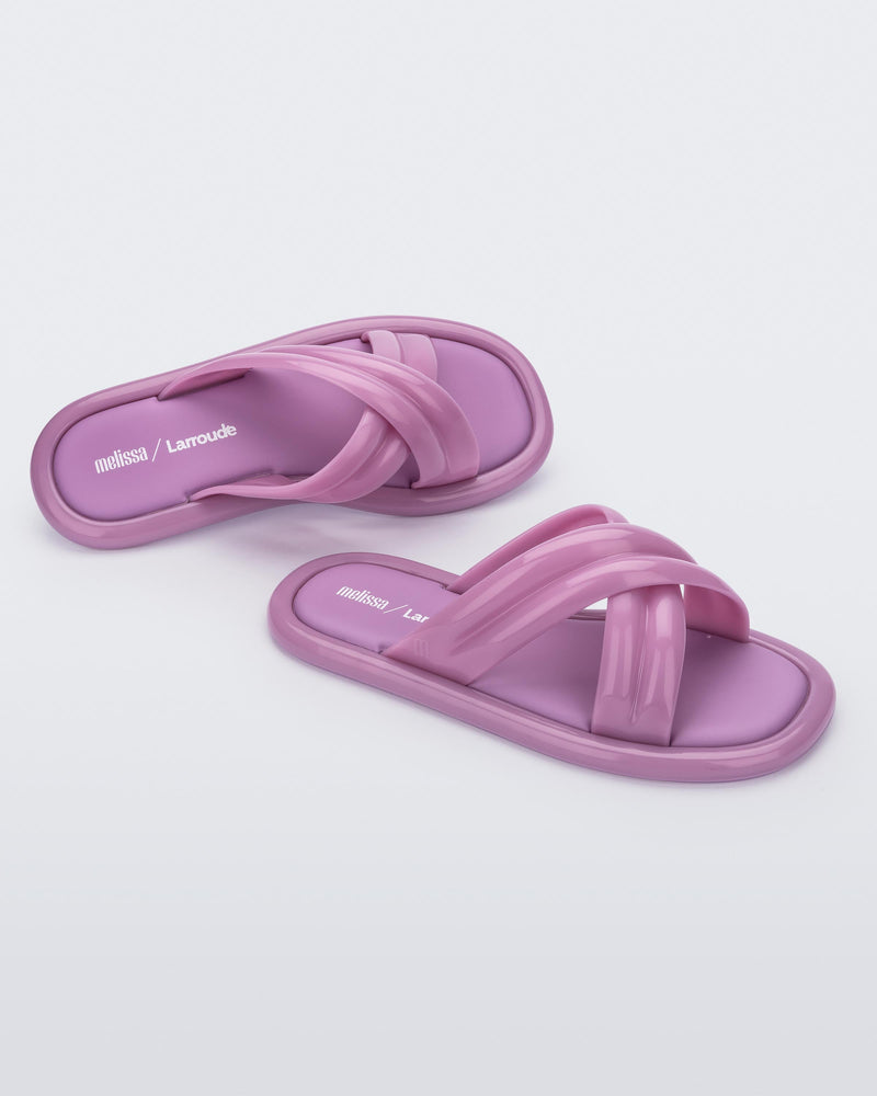 Top and angled view of a pair of lilac Melissa Cali slides with cross straps.