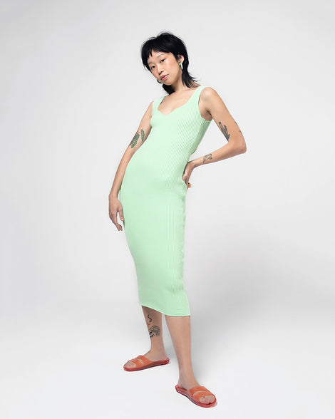 A model posing for a picture in a green dress and a pair of clear orange Melissa Real Jelly Slides with two front straps.
