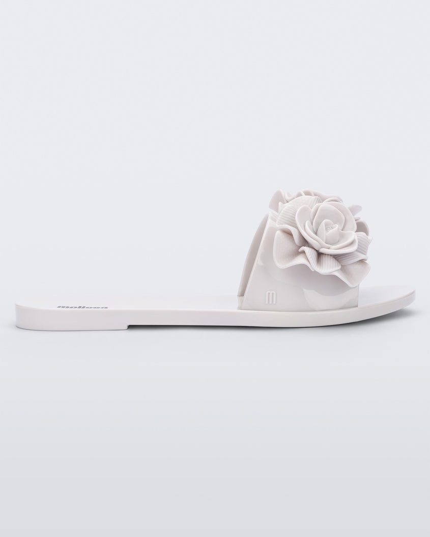 Side view of a white Melissa Babe Garden slide with two flowers on the front strap.