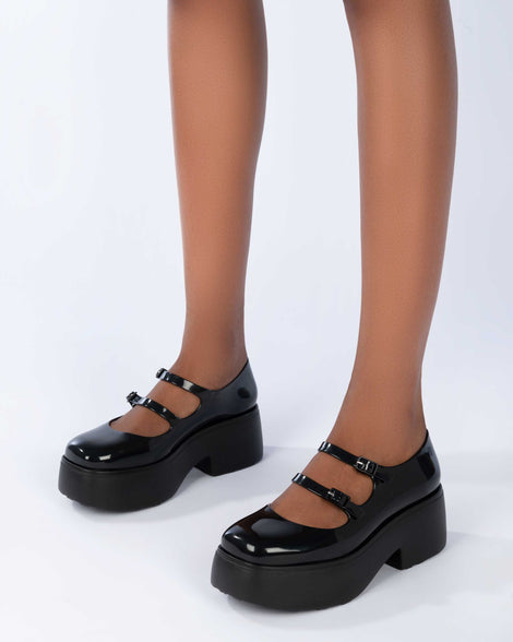 A model's legs wearing a pair of black Melissa Farah platforms with two top straps.