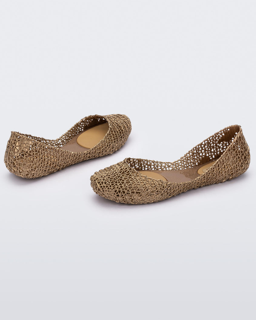 Angled view of a pair of Melissa Campana flats in gold with an open woven texture.