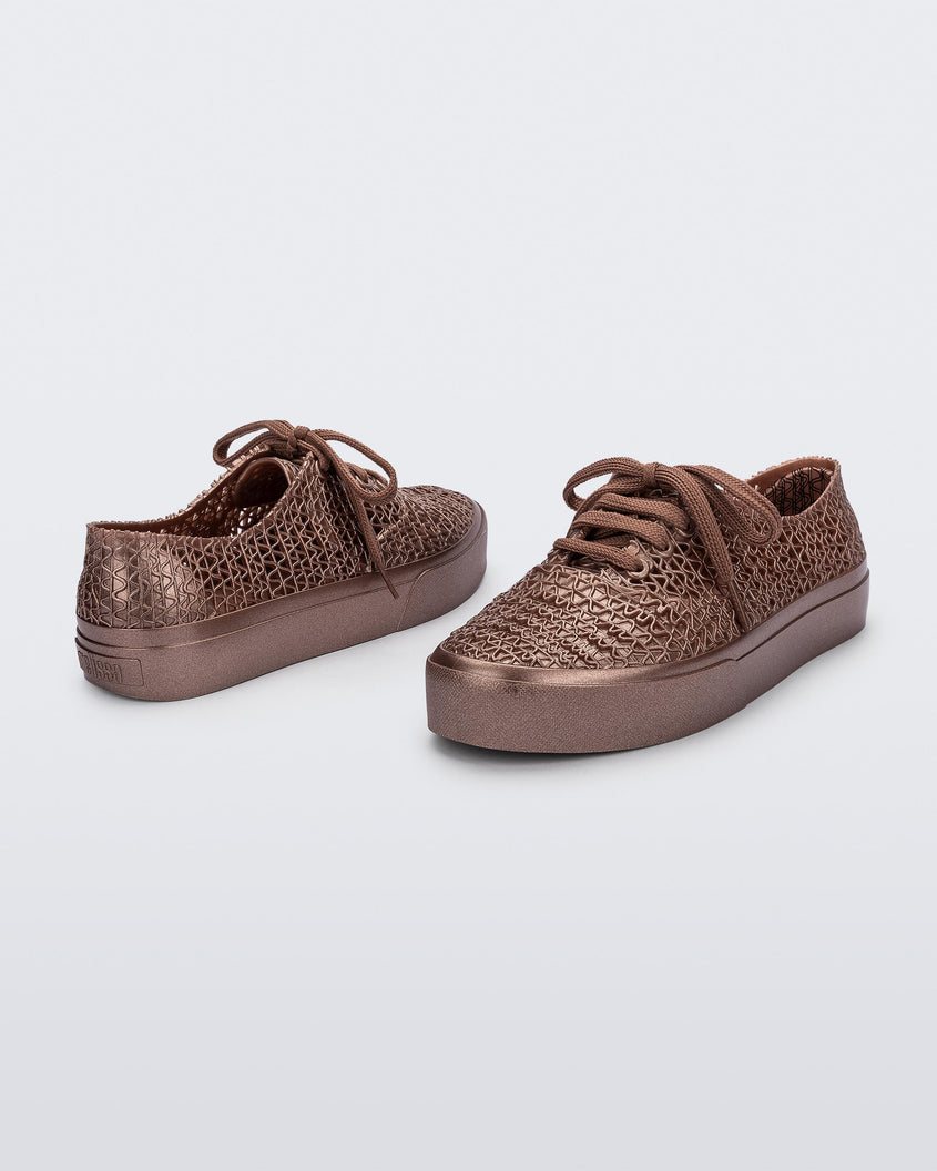 A front and back view of a pair of Melissa Campana Metallic Pink sneakers with a woven texture base and laces.