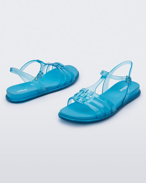 Front and back view of a pair of Melissa Party sandals in transparent blue with back ankle strap and buckle closure