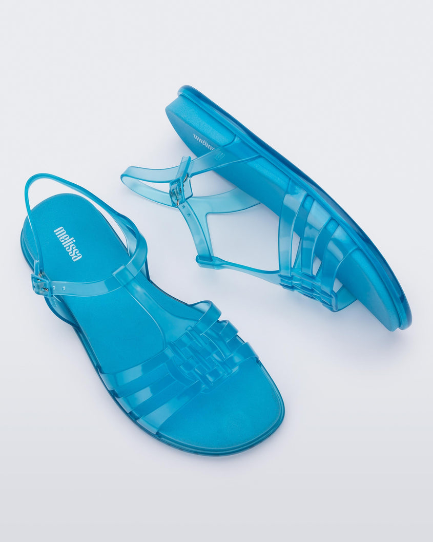 Top and side view of a pair of Melissa Party sandals in transparent blue with back ankle strap and buckle closure