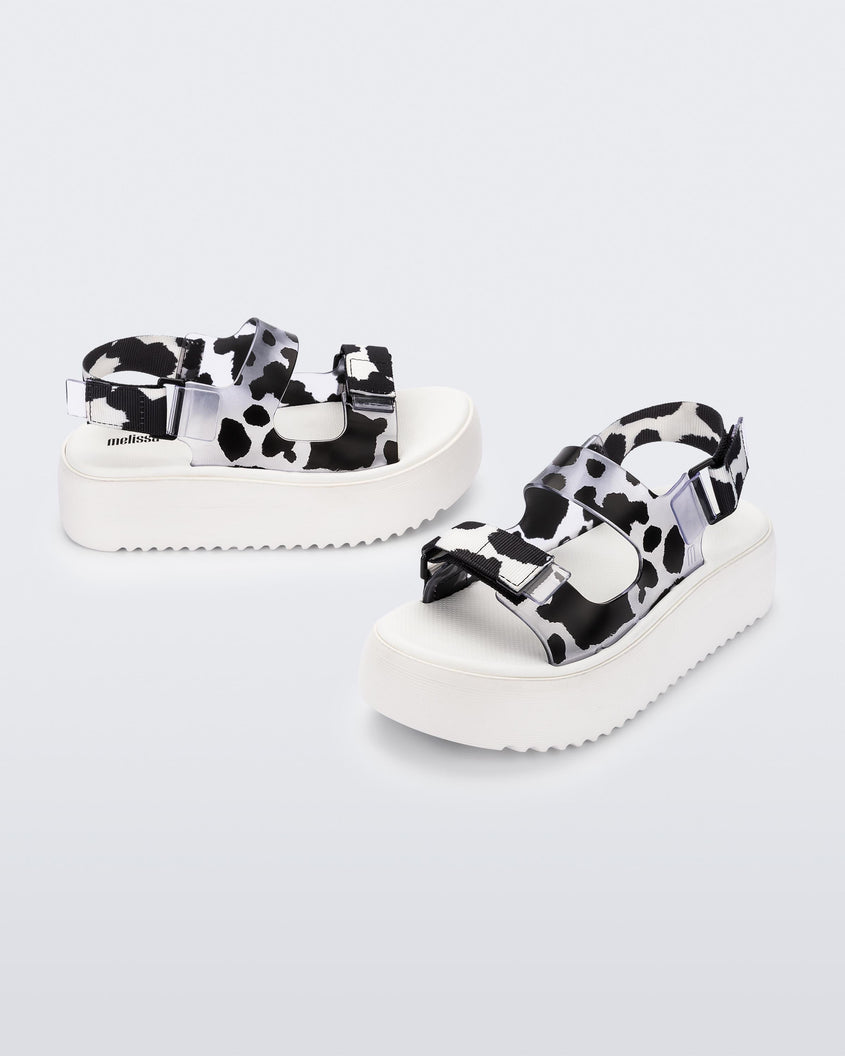 Angled view of a pair of white Melissa Brave Papete platform sandals with black spotted straps.