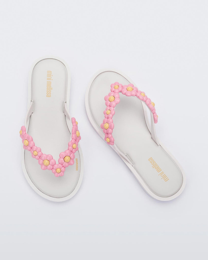 Top view of a pair of white Mini Melissa Spring Flip Flops with yellow and pink flowers.