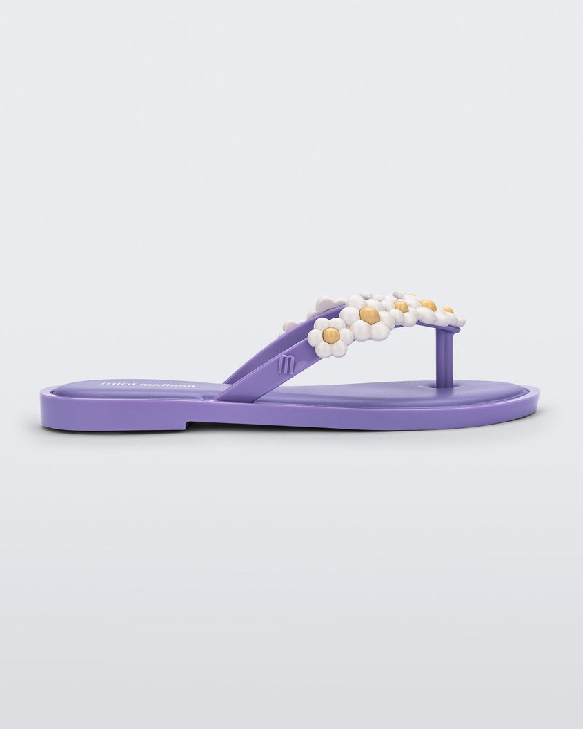 Side view of a lilac / white Mini Melissa Spring Flip Flop with white and yellow flowers.