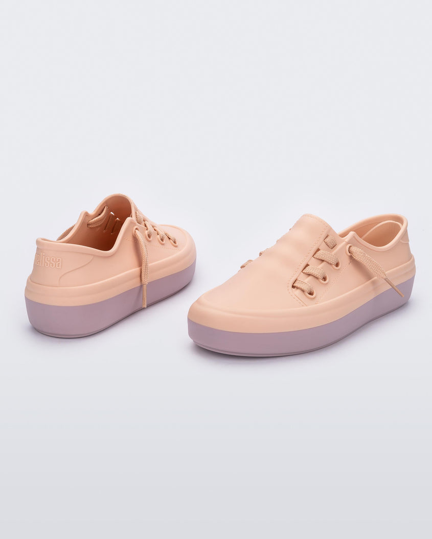 An angled front and back view of a pair of pink Melissa Ulitsa sneakers with a pink base and laces.