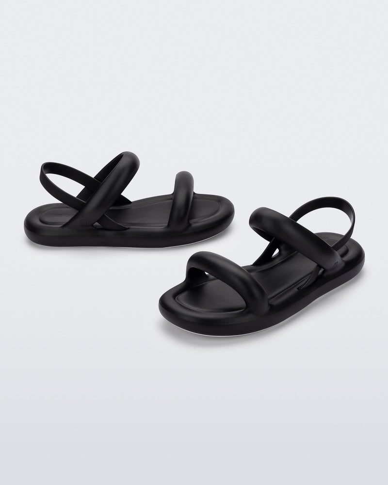 An angled side and front view of a pair of black Melissa Free Bloom sandals with puffer-like straps.
