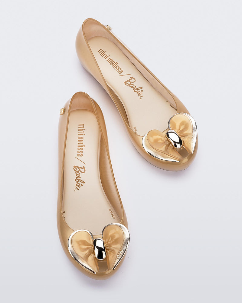 Top view of a pair of Pearly Beige Mini Melissa Ultragirl flats with a heart buckle bow detail on the toe.