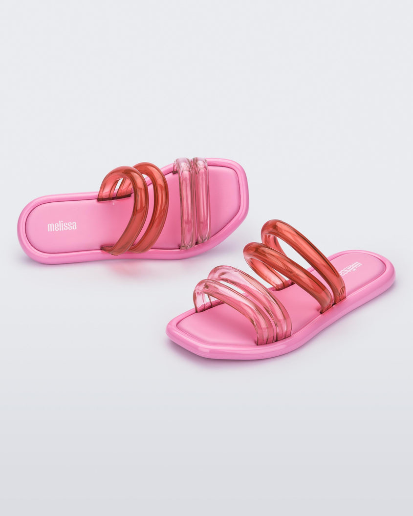 Top and angled view of a pair of pink and transparent pink Melissa Airbubble slides.
