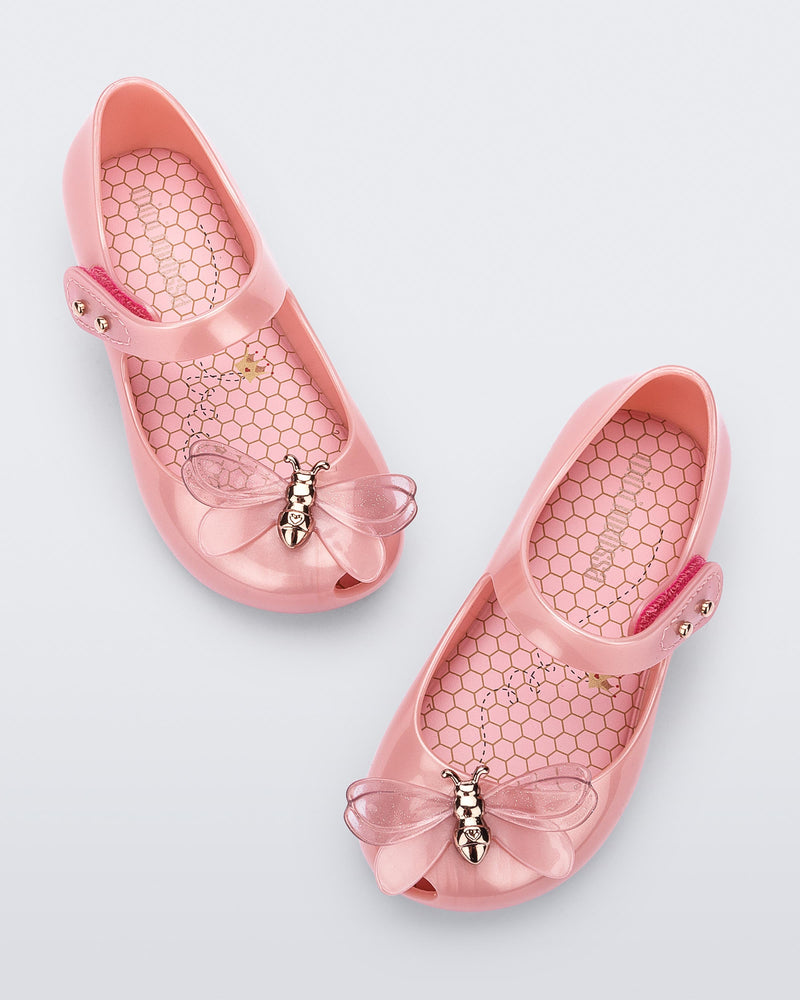 Top view of a pair of pearly pink Mini Melissa Ultragirl Bugs flats with a top strap and a bug detail on the toe.