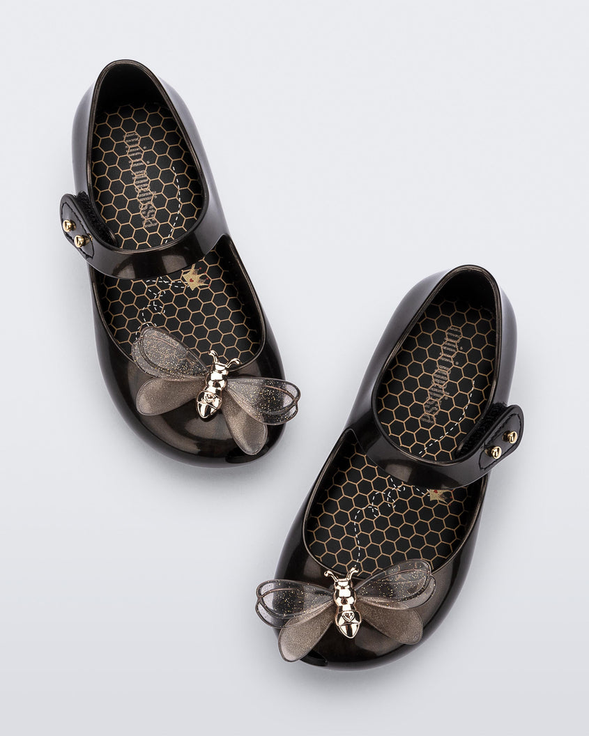 A top view of a pair of metallic black Mini Melissa Ultragirl Bugs flats with a top strap and bug detail buckle on the toe.