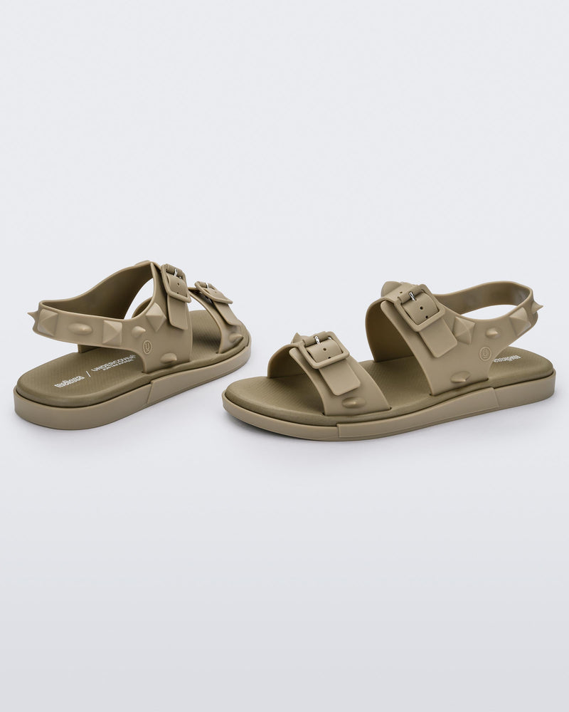 A side and back view of a pair of beige Melissa Spikes Sandals with two straps with buckles on top and spike details around the base.