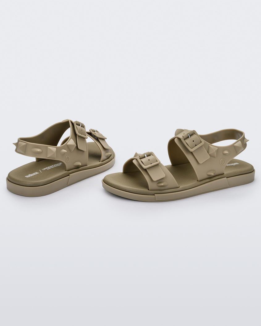 A side and back view of a pair of beige Melissa Spikes Sandals with two straps with buckles on top and spike details around the base.