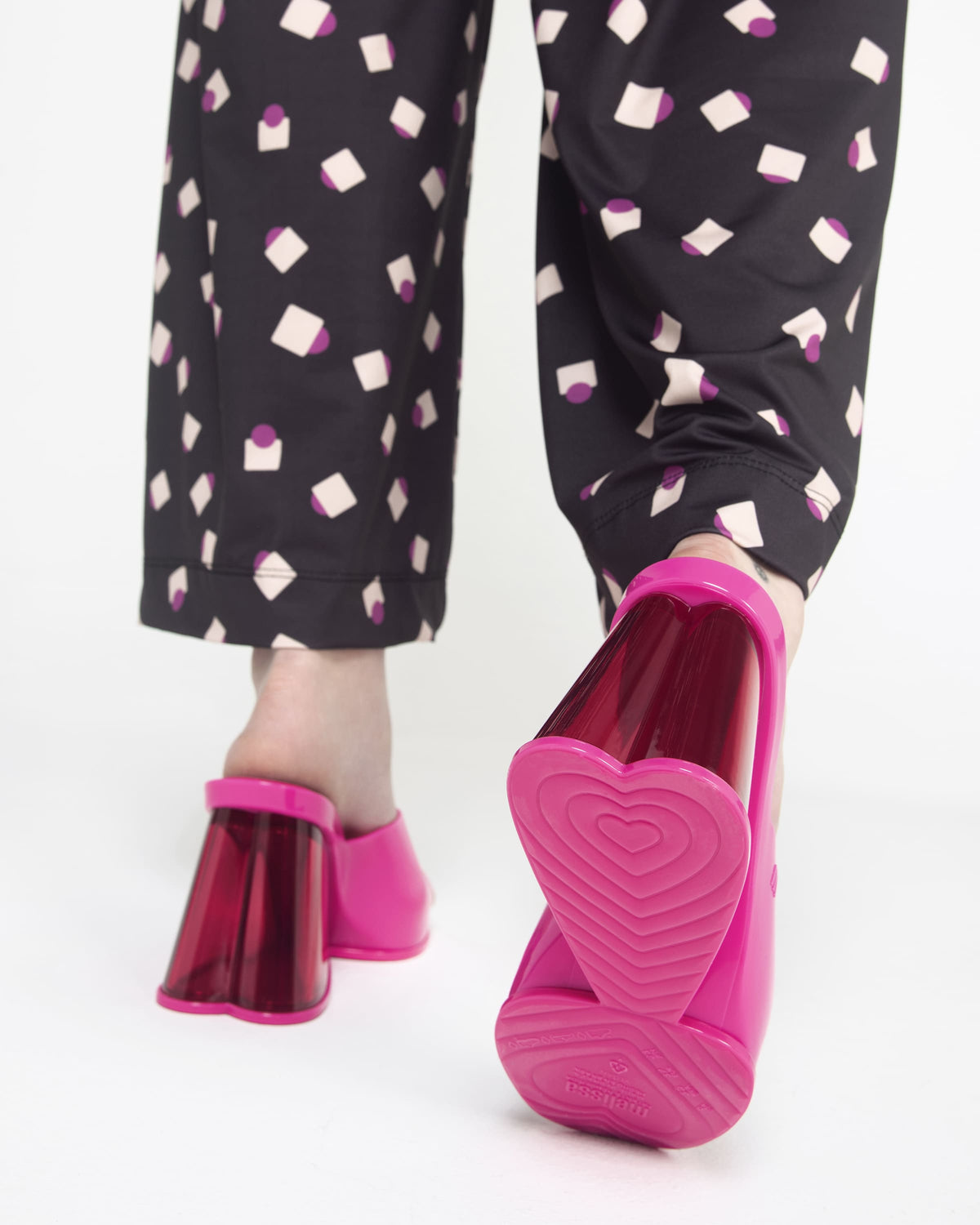 A back and close up view of a model's legs wearing a pair pink Melissa Darling heels with clear soles.