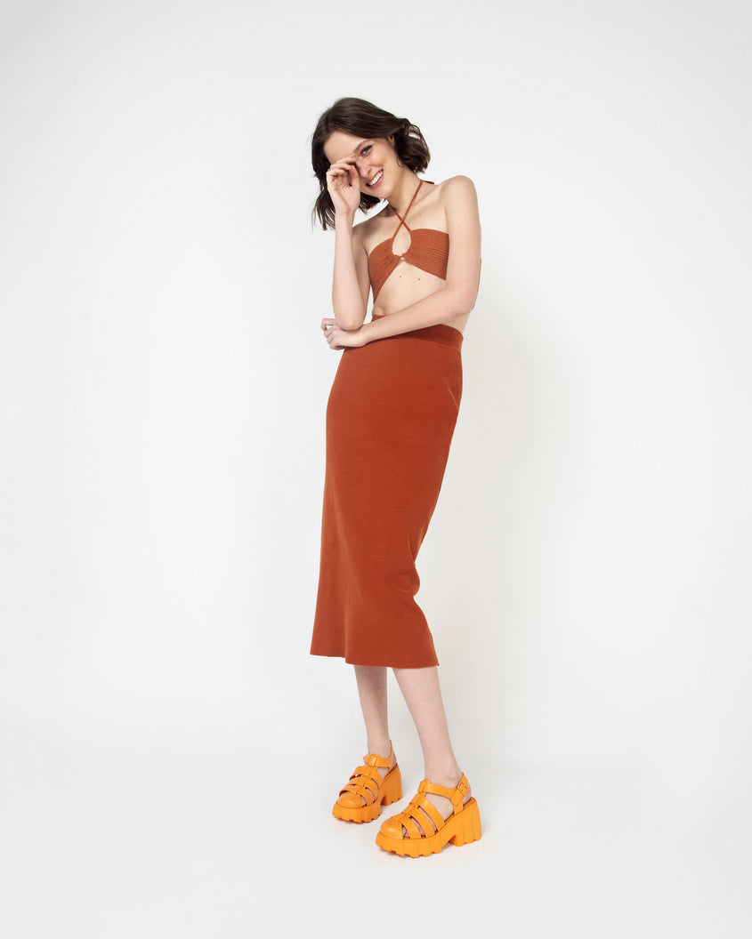 A woman in a brown dress wearing a pair of orange Melissa Megan planform heel sandals.