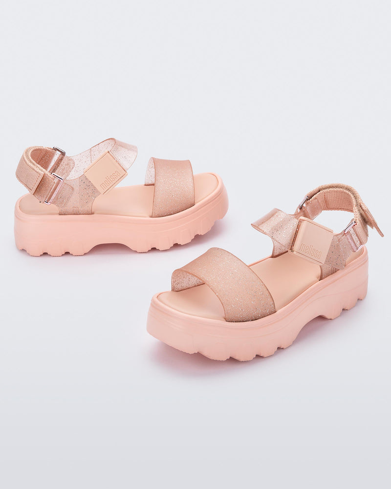 An angled top and side view of a pair of beige/glitter beige platform Melissa Kick Off Sandals with two straps.