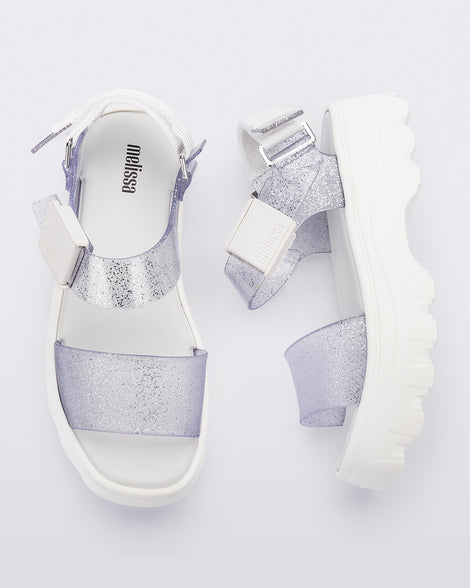 A top and side view of a pair of white/glitter clear platform Melissa Kick Off Sandals with two glitter straps.