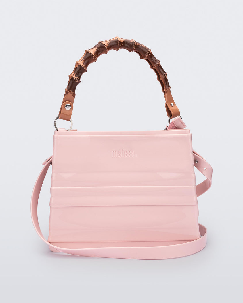 Back view of the Melissa Tie handag in pink with long shoulder strap and natural colored bamboo shaped top handle.