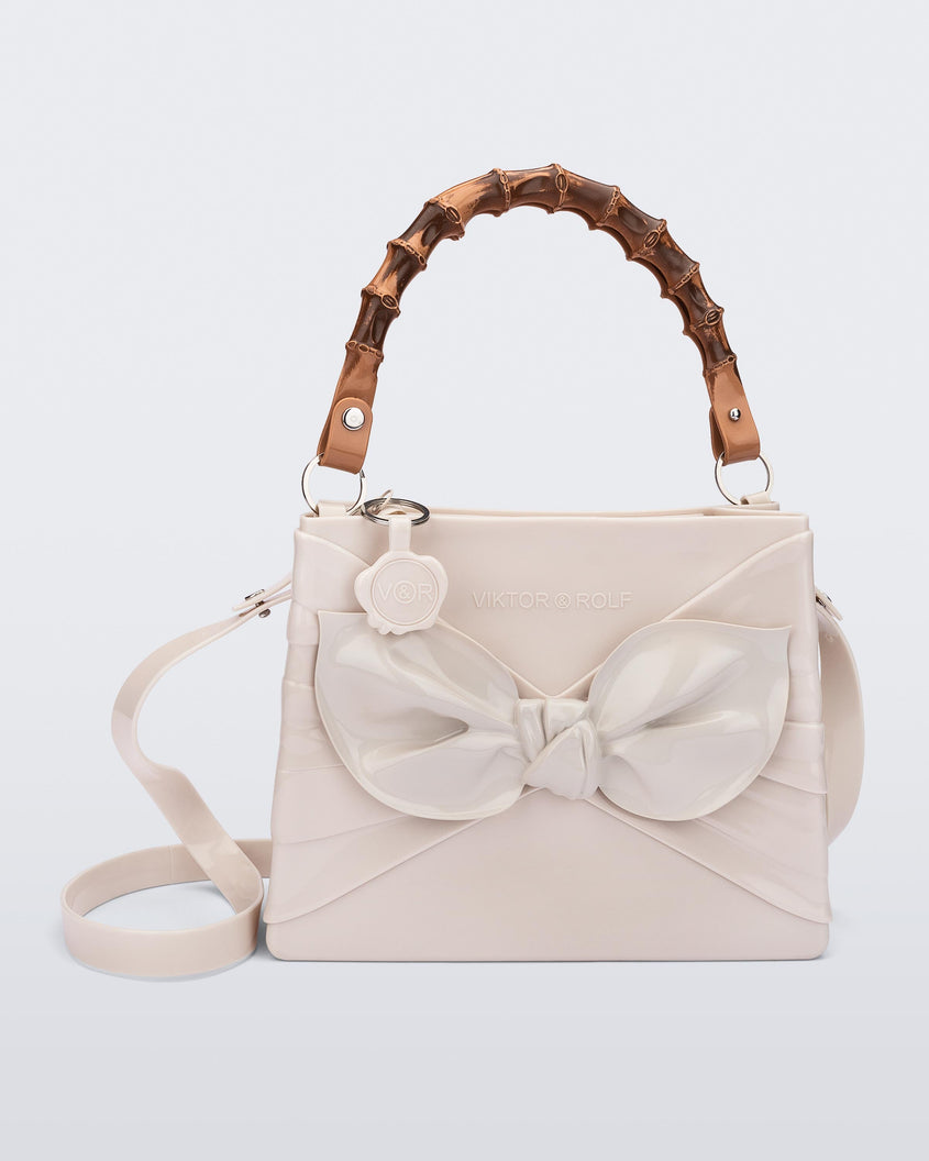 A front view of a beige Melissa Tie Bag with a bow detail on the front, two bamboo top straps and a beige shoulder strap.