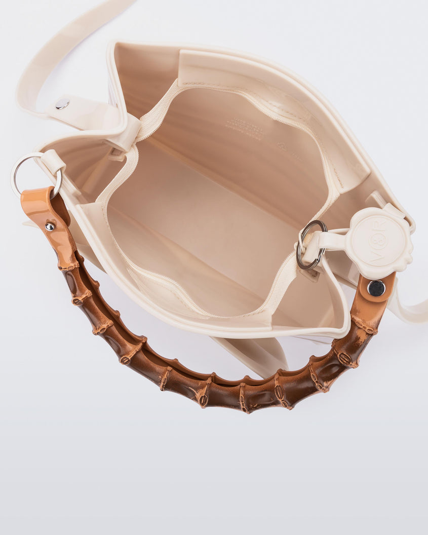 A top view of the inside of a beige Melissa Tie Bag with a bow detail on the front, two bamboo top straps and a beige shoulder strap.