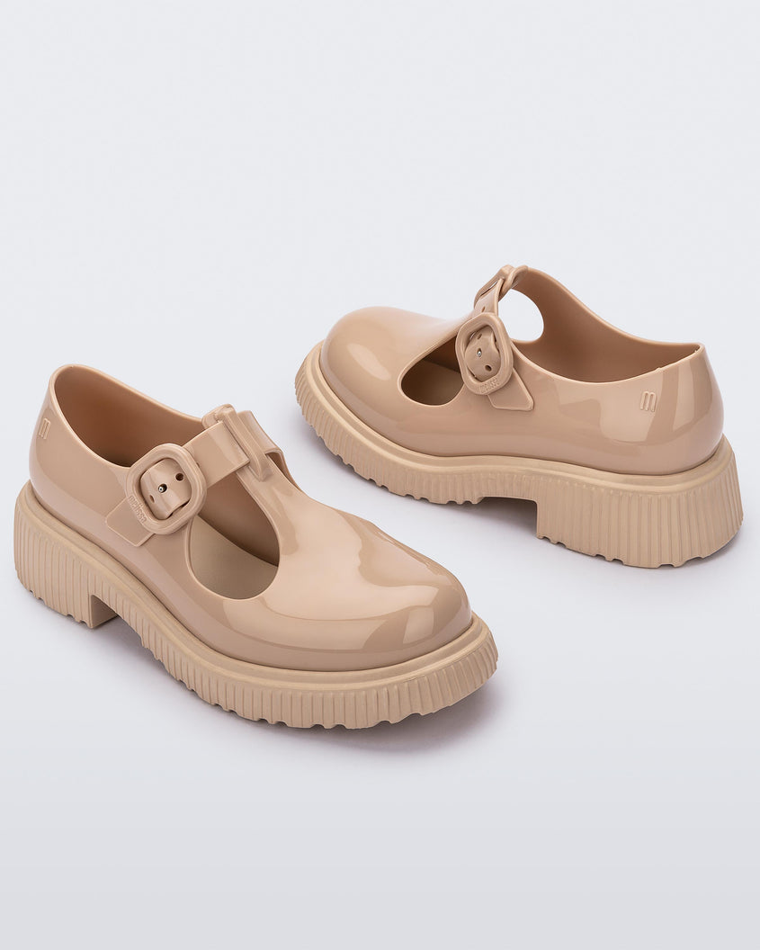 Angled side view of a pair of beige Mini Melissa Jackie loafers with two cut outs and a buckle detail strap.