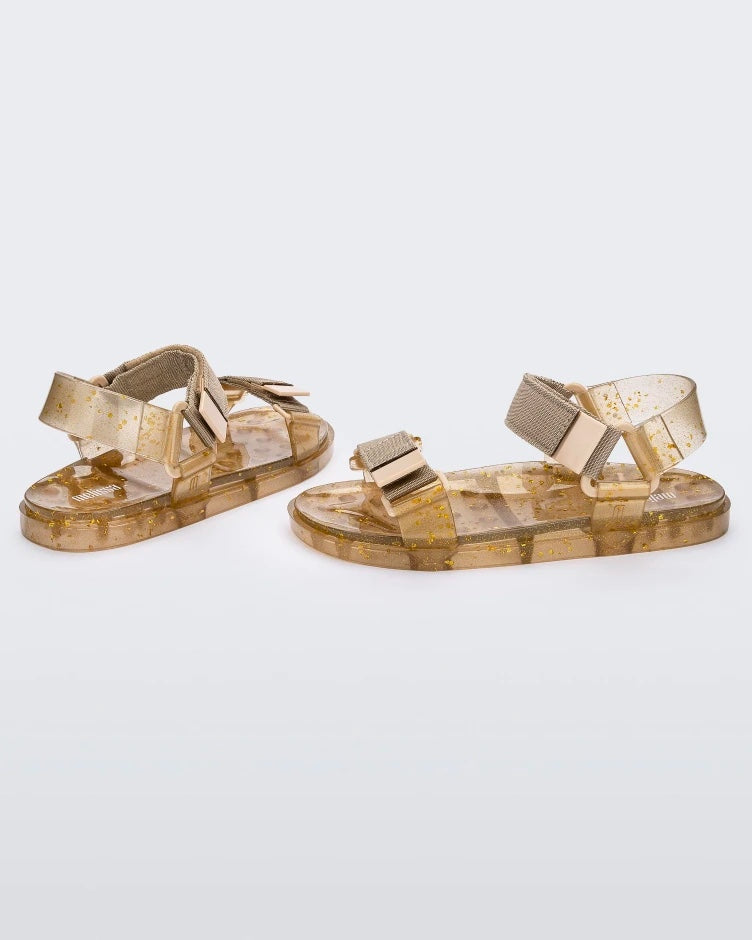 Angled view of a pair of Melissa Wide Papete sandals with transparent beige glitter sole and beige velcro straps.