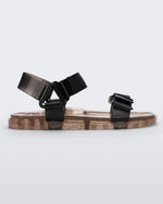 Side view of a Melissa Wide Papete sandal with transparent gold glitter sole with black velcro straps