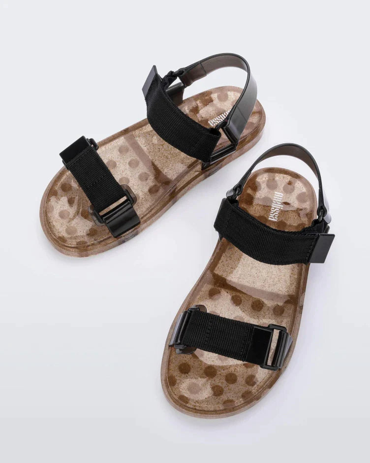 Top view of a pair of Melissa Wide Papete sandals with transparent gold glitter sole with black velcro straps