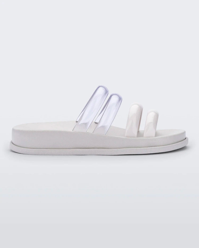 Side view of a white/clear Melissa Soft Wave Slide with 4 straps: two clear and two white.