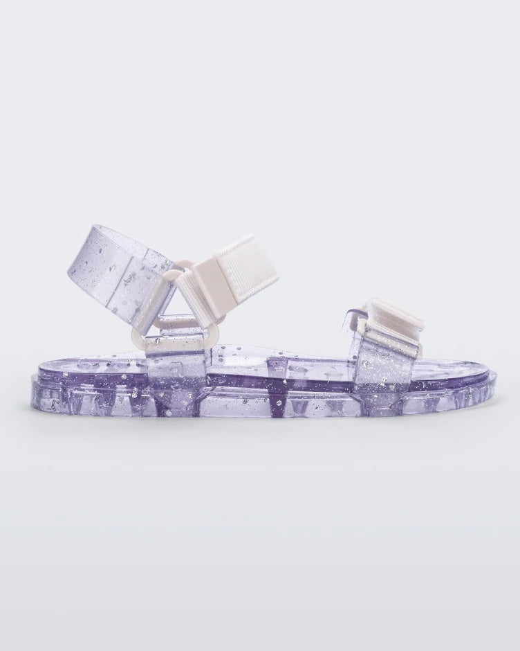 Side view of a Melissa Wide Papete sandal with transparent silver glitter sole with white/clear velcro straps